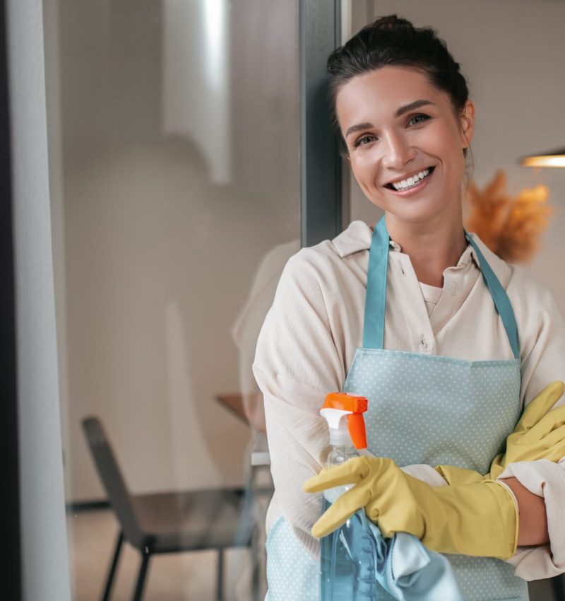 domestic-routine-smiling-housewife-apron-standing-kitchen-min